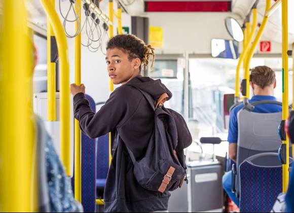 Young person standing on a bus.