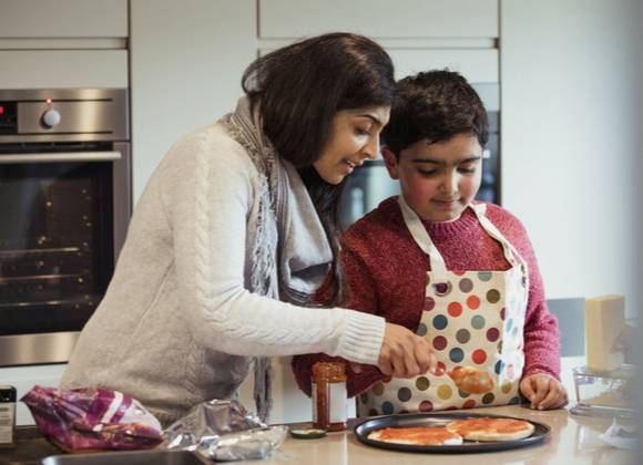 Parent and child cooking in home kitchen.