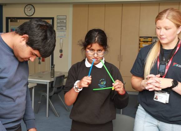 Two young people in music class at school with teacher.