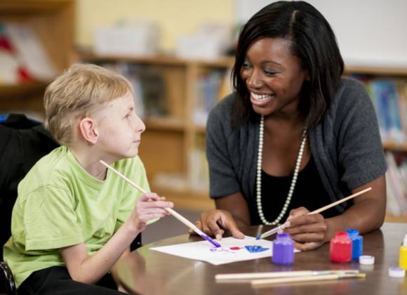 Young child with adult doing painting in educational setting.