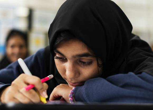 Young person at desk in educational setting.