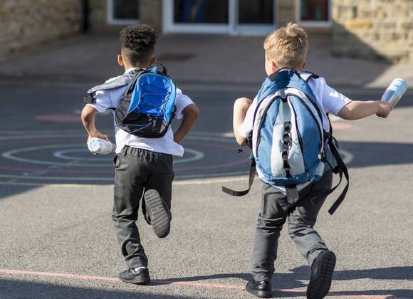 Two young children running towards school entrance.