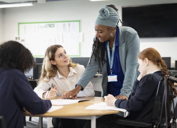 Three young people with teacher in educational setting.